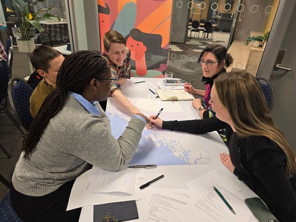 Deltakere sitter og arbeider sammen rundt et bord.